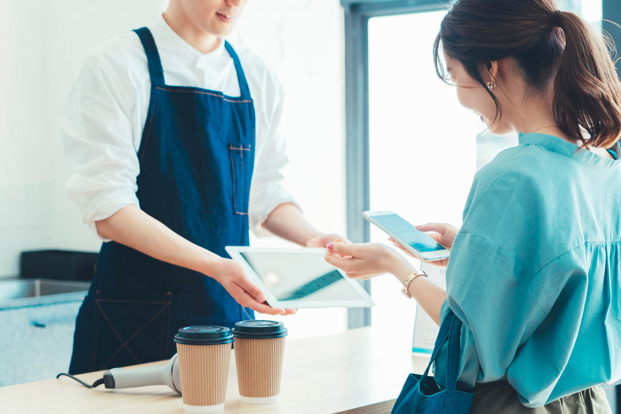 レジでの会計でスマホ決済の準備をする女性